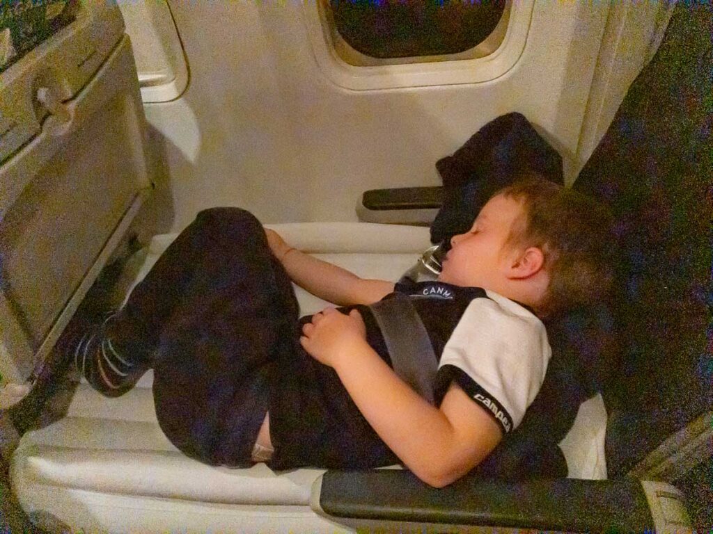 a toddler from the Baby Can Travel website, sleeps soundly on a long haul flight on top of his FlyAway Kids bed.