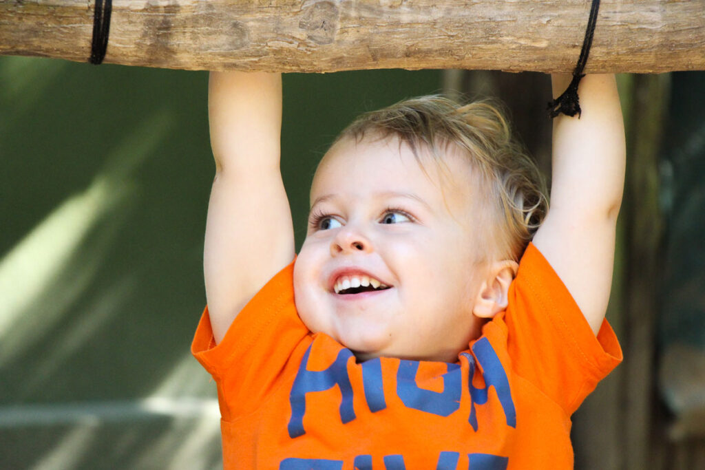 a young child smiles while playing during a family road trip with a toddler.