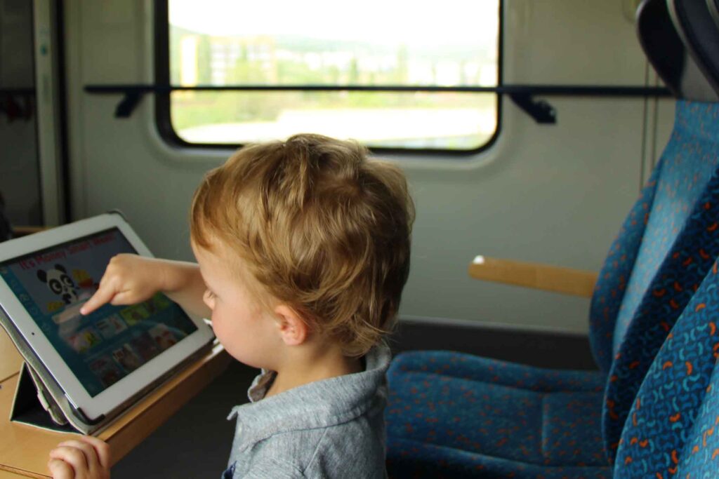 A toddler from BabyCanTravel.com uses a digital library reading app on a train.