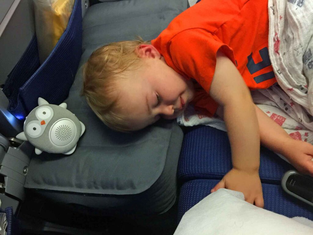 a toddler is fast asleep on an airplane on a family holiday.