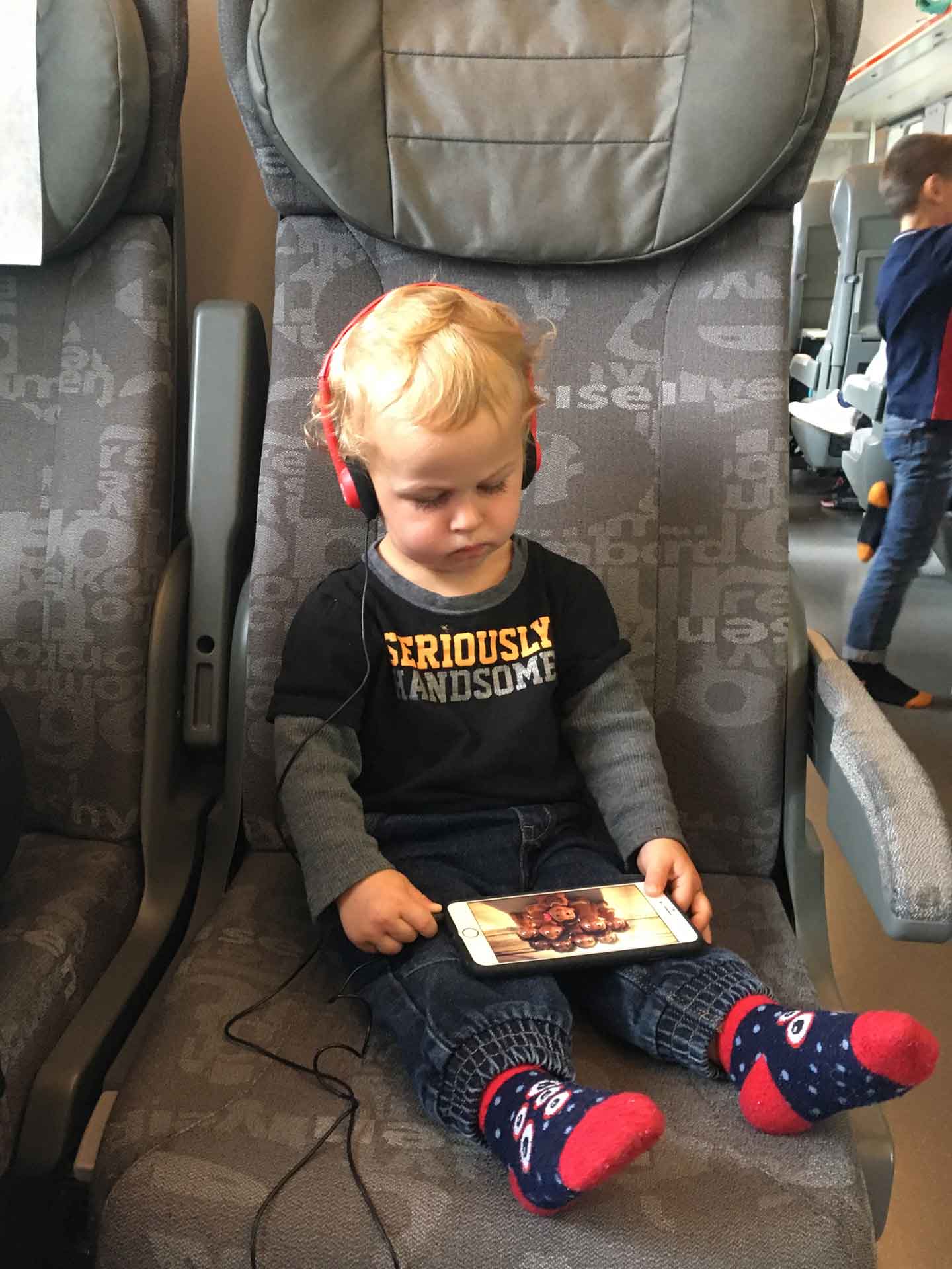 A toddler, from BabyCanTravel.com, uses volume-limiting headphones to watch a show on an iPad during a flight.