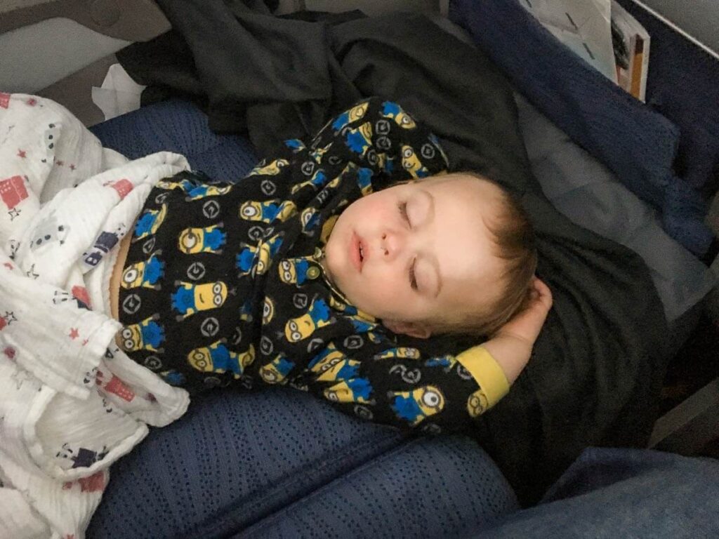 a child, from BabyCanTravel.com, sleeps on an inflatable airplane bed for toddler.
