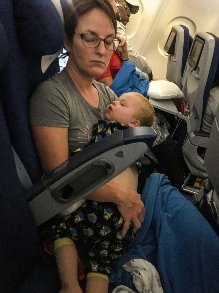 Celine Brewer, owner of BabyCanTravel.com, is flying with toddler on lap, both asleep.