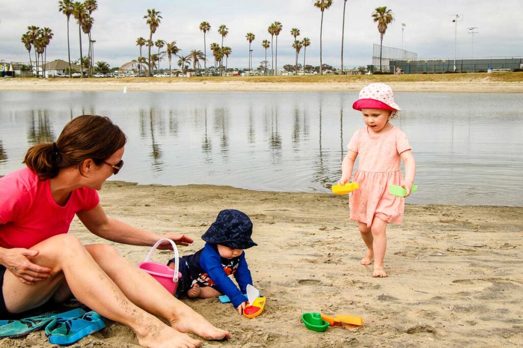 A baby plays in the sand and a toddler fetches water on Mission Beach on a family trip to San Diego.