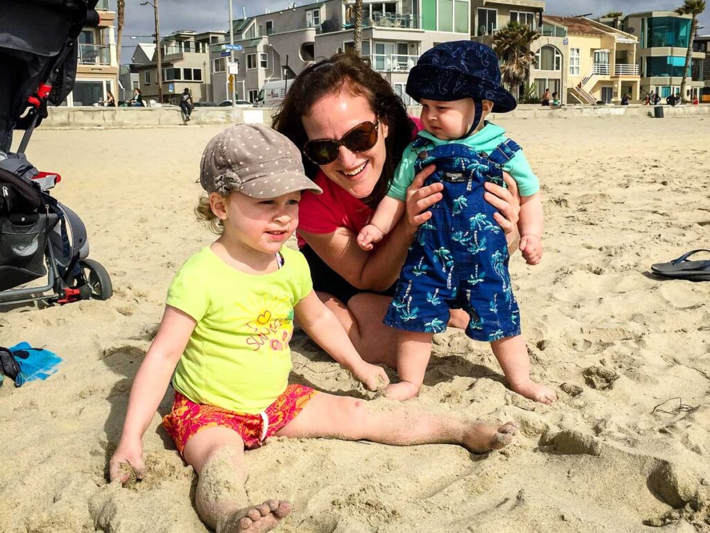 a mom plays with her young kids on Mission Beach on a family trip to San Diego, California.