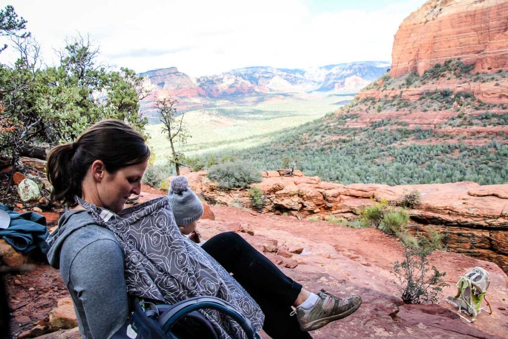 a mom enjoys an amazing view breastfeeding while hiking with a baby in Sedona, AZ