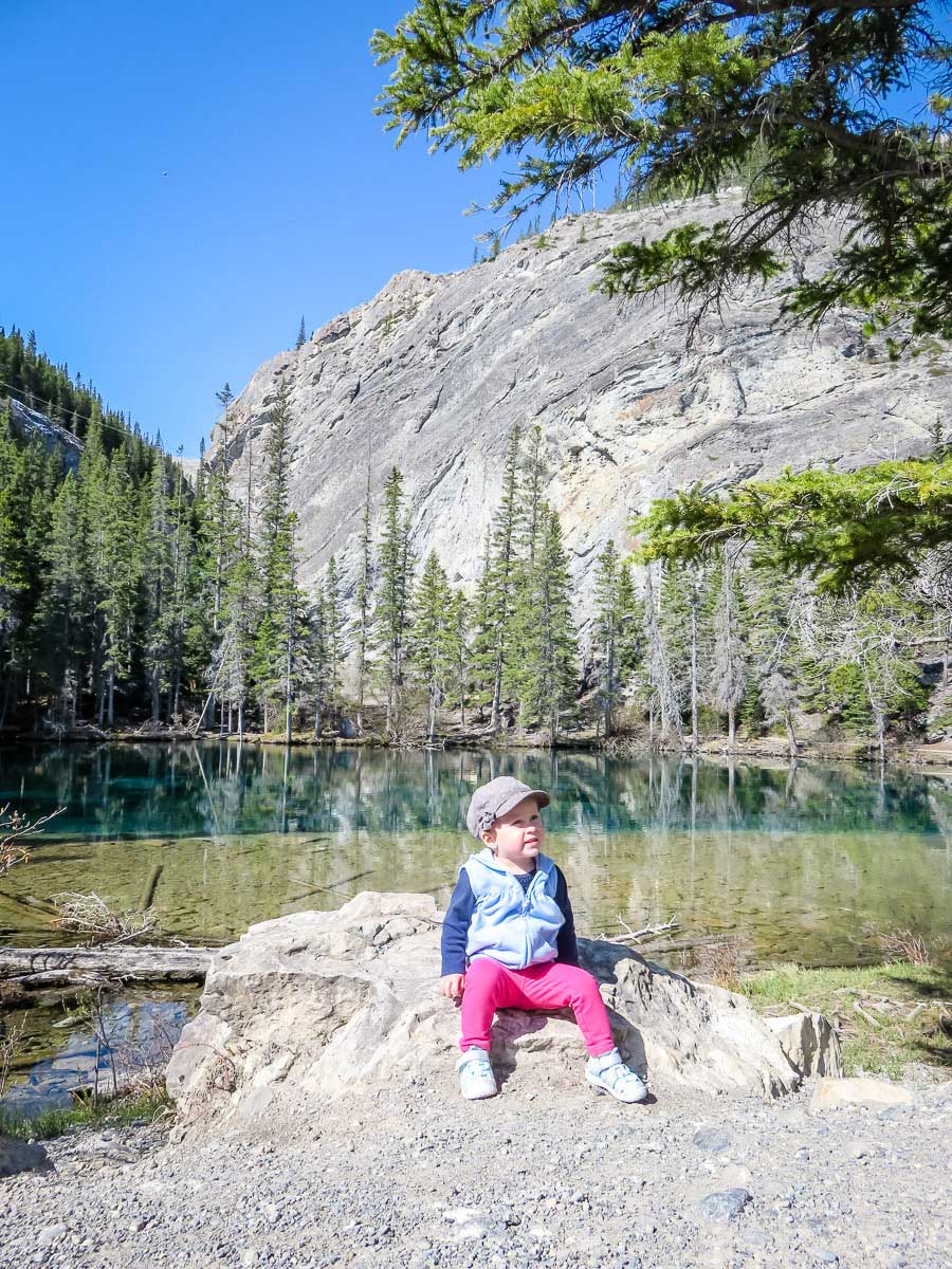 a toddler rests on a rock after a family hike to Grassi Lakes, Canmore, Alberta.