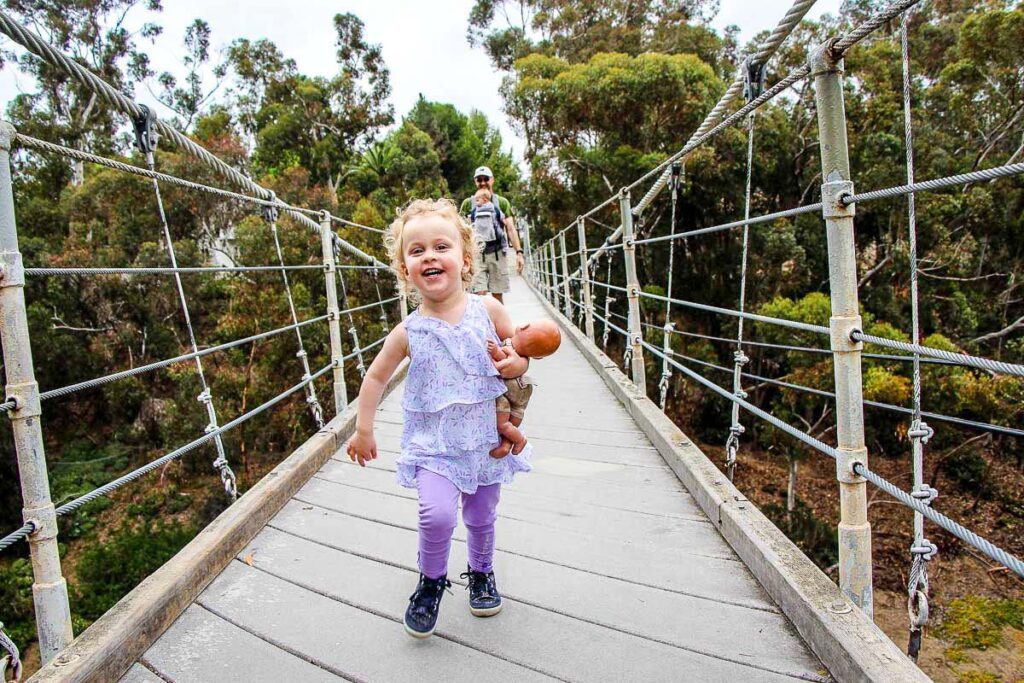 A toddler races across the Spruce Street Suspension Bridge on an easy walk near Balboa Park in San Diego, Califonia.