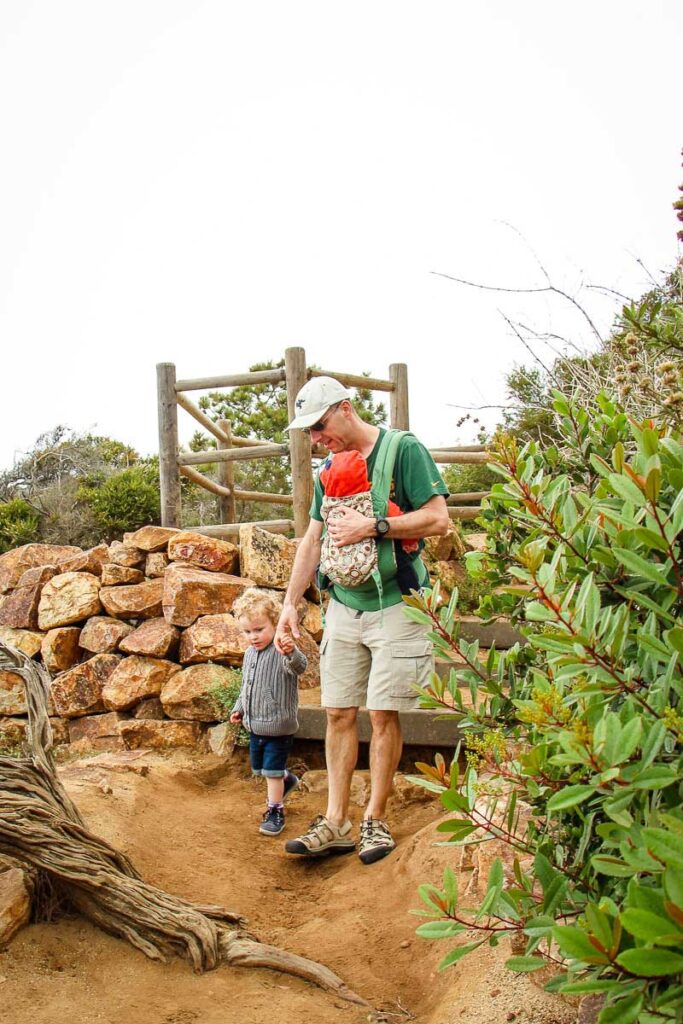 A father with his baby and toddler enjoy a fun walk at the Torrey Pines Natural Reserve just outside San Diego.