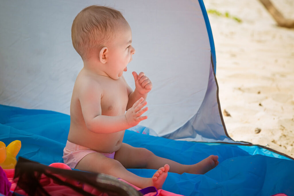 baby sitting in a baby beach tent