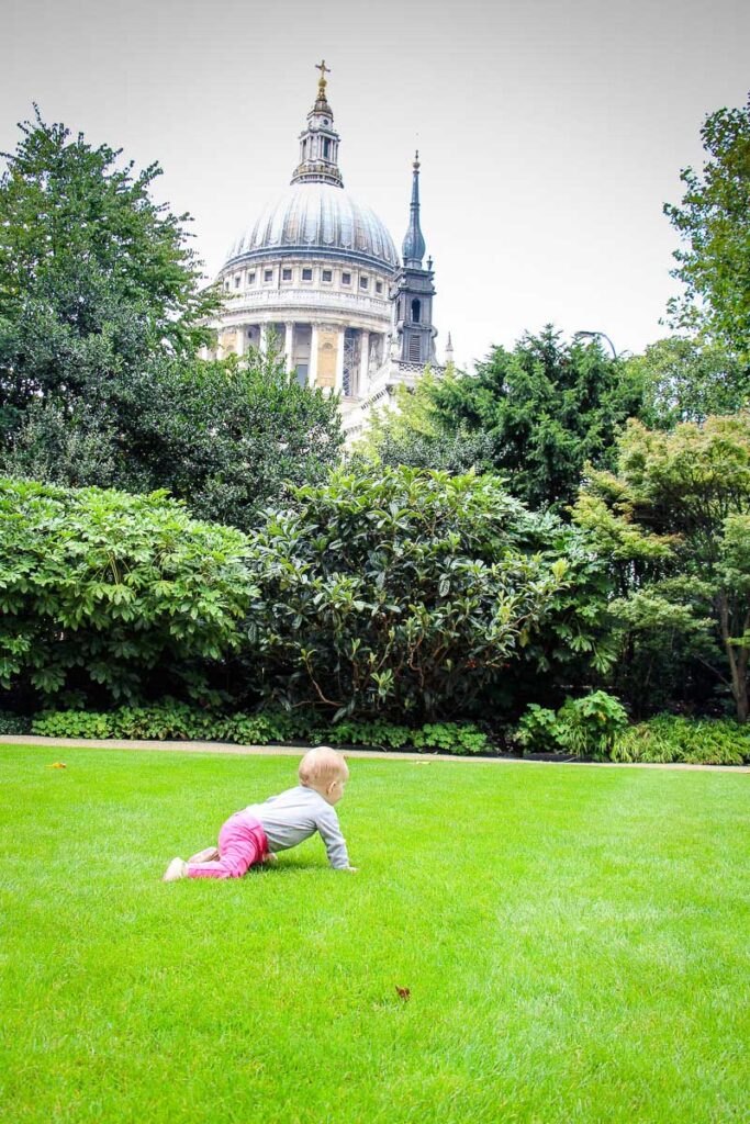 Baby crawling on grass in front of St Pauls Cathedral in London