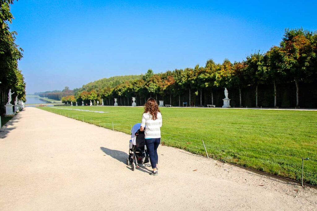 a mother walks her baby in a stroller during nap time at the Palace of Versailles in Paris, France.
