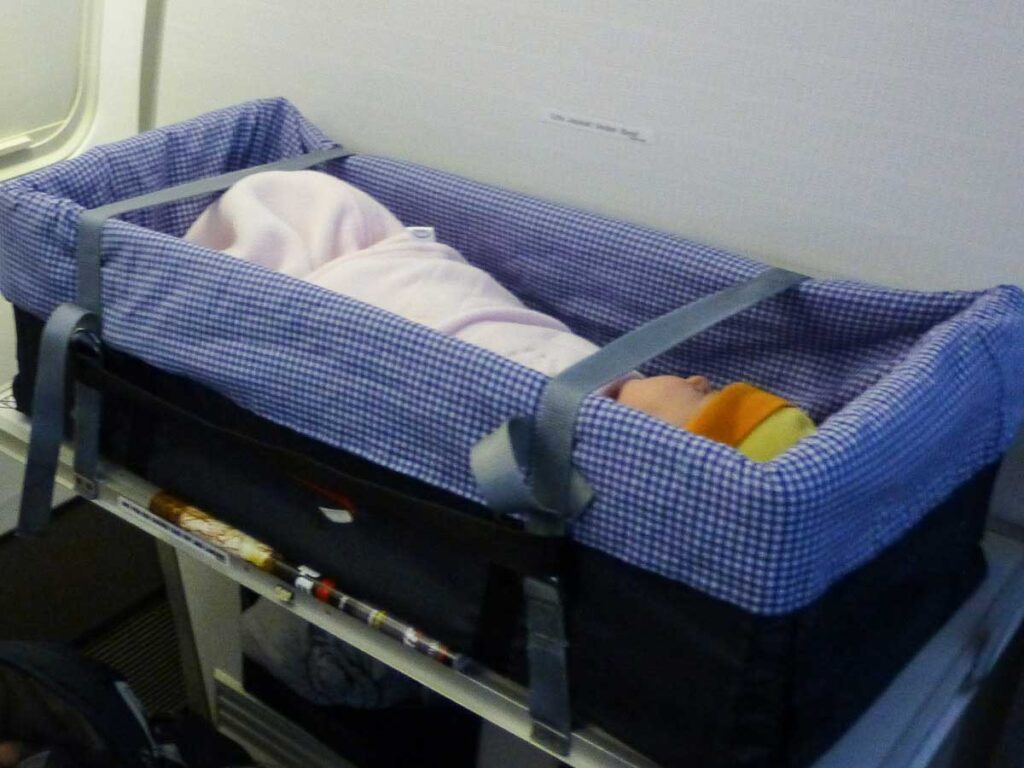 a baby from the BabyCanTravel family sleeps in an airplane bassinet while wearing a sleepsack.