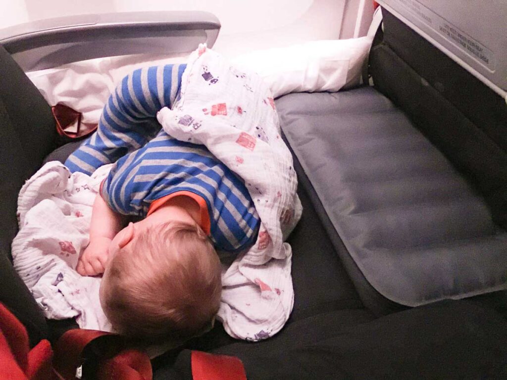 a toddler from Baby Can Travel sleeps on an inflatable airplane travel bed, which we feel belongs on our list of best baby gear for travel.