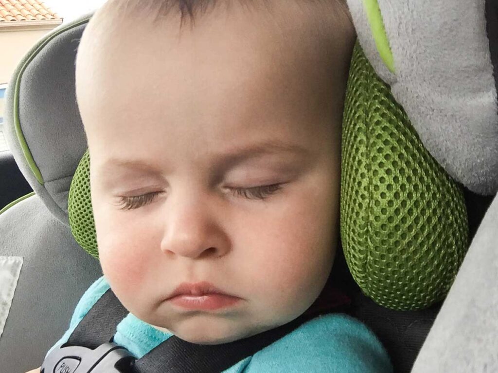 a baby naps on the go in travel car seat.