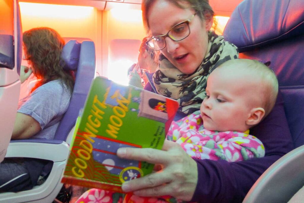 a mother reads Goodnight Moon to her baby in hope of getting her to sleep on vacation.