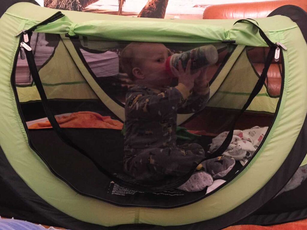 a child from the Baby Can Travel family prepares to sleep in his KidCo Peapod, toddler travel tent, on a family vacation.