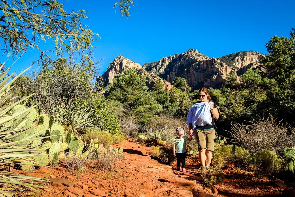 Celine Brewer, owner of BabyCanTravel.com, hikes the Huckaby Trail in Sedona, AZ with her toddler and a baby in a carrier.