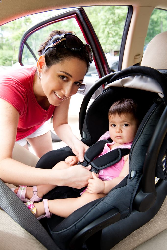 mother places baby in a front facing car seat in the back seat of a car