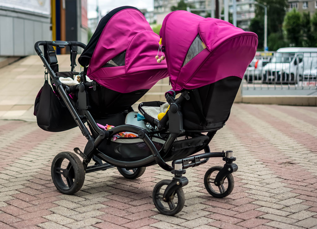 A Double Travel Stroller with a bright pink canopy.