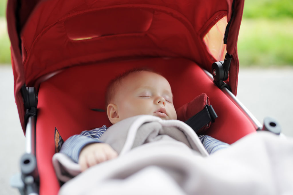 a baby sleeps in a travel stroller for infant.