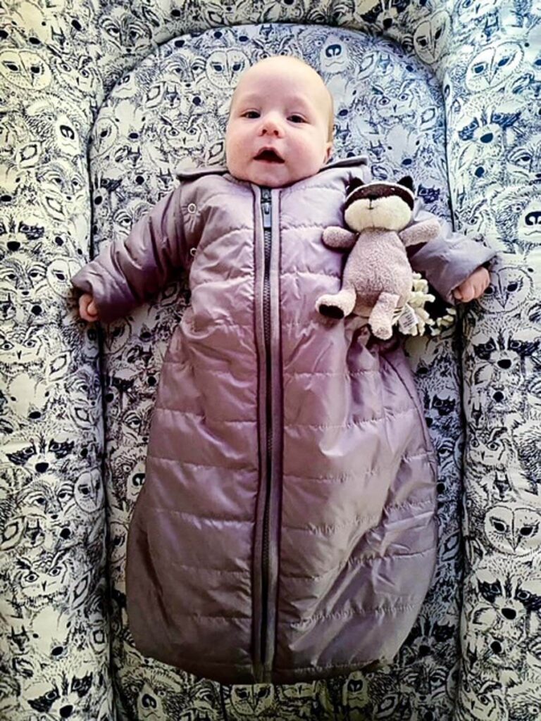 a baby wearing Baby Deedee baby sleeping bag for camping.