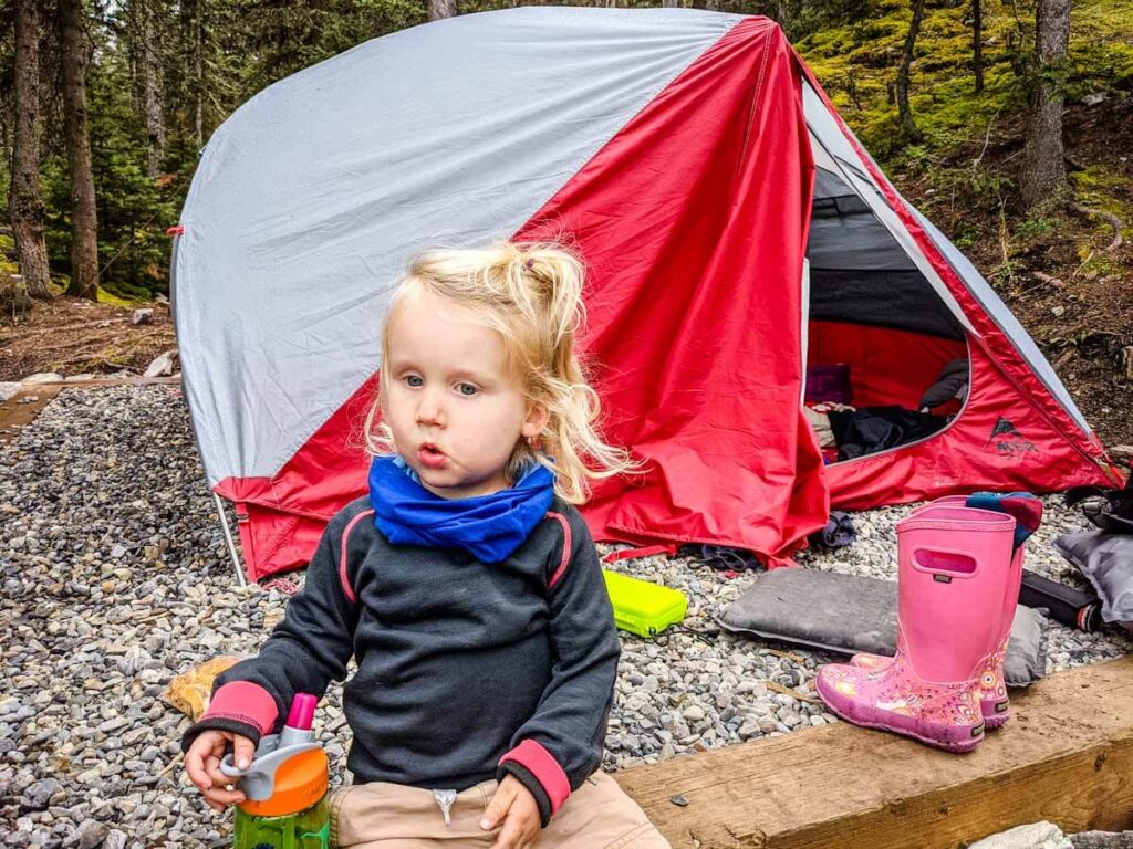 Toddler outside of the tent with camping gear around