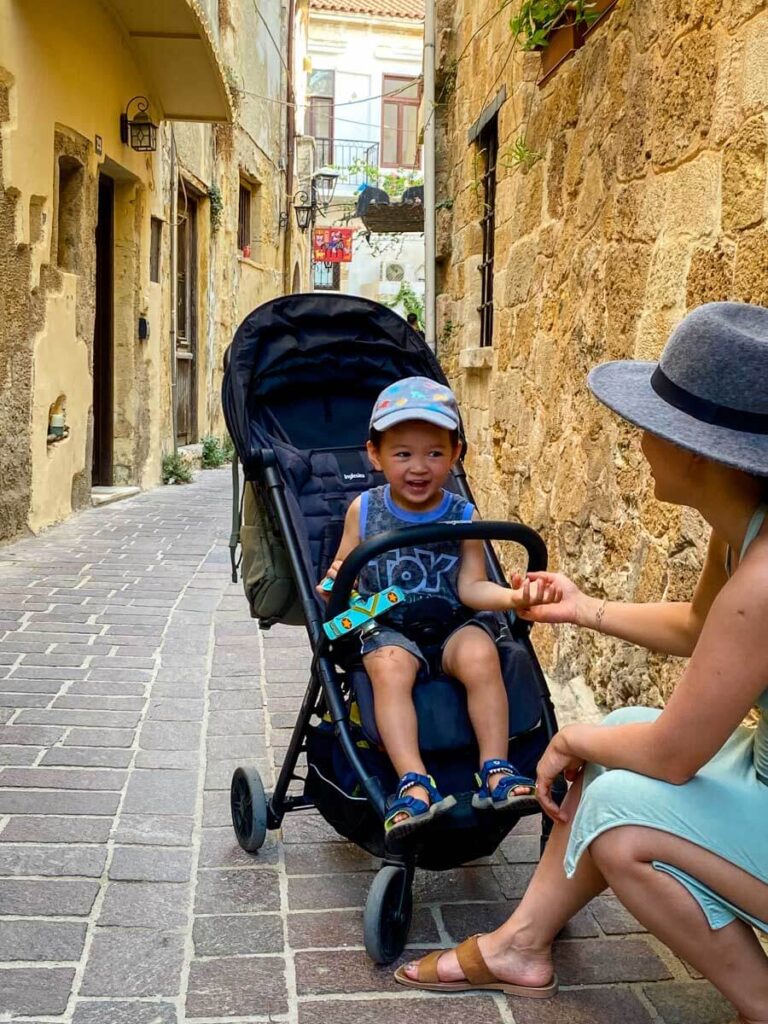 a happy toddler sitting in Inglesina Quid travel stroller on a family vacation to Greece.