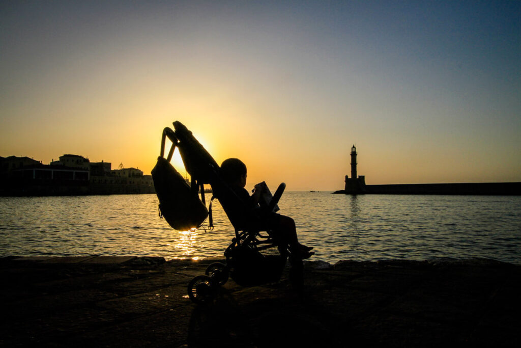 Toddler in travel stroller at sunset in Greece.