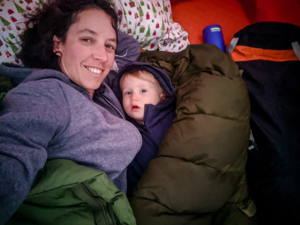 mother and toddler inside sleeping bags while on a family camping trip.