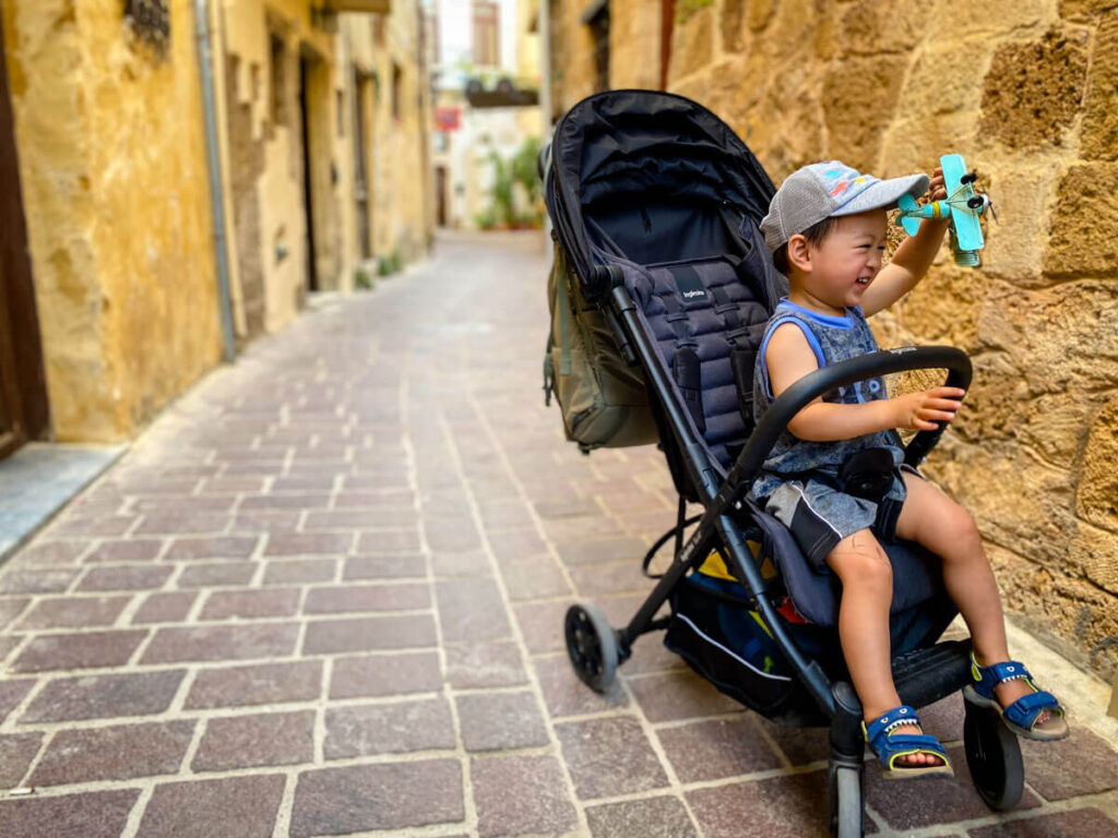  a Toddler playing with toy in an Inglesina Quid compact lightweight stroller.