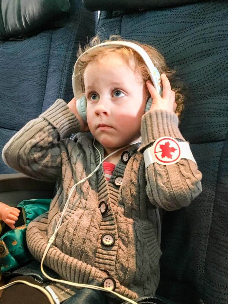 a toddler from the BabyCanTravel.com family wears wearing toddler headphones for plane trips.