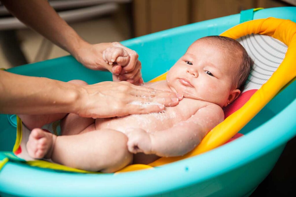 Infant getting bath in portable baby bathtub