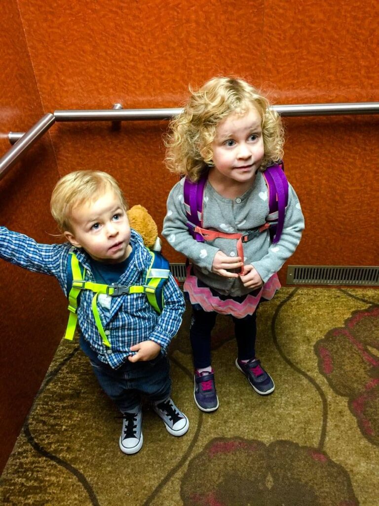 toddler wearing backpacks in an elevator