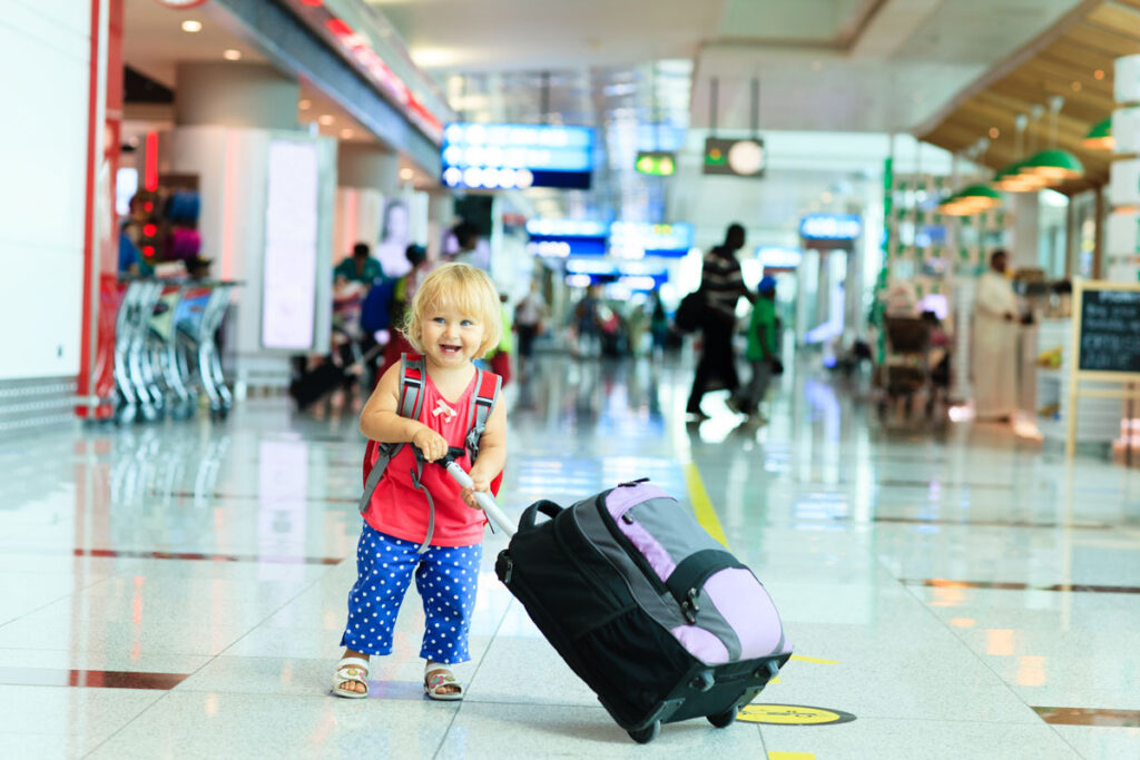 toddler in airport holding up suitcase