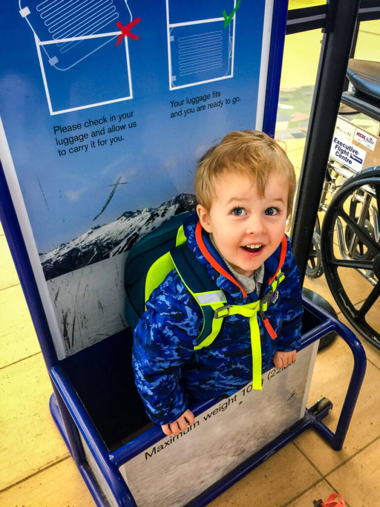 toddler in luggage size checker at airport