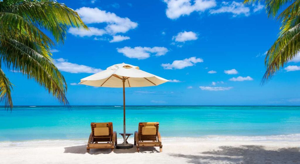 two beach chairs under an umbrella - a typical tropical scene at baby friendly resorts.
