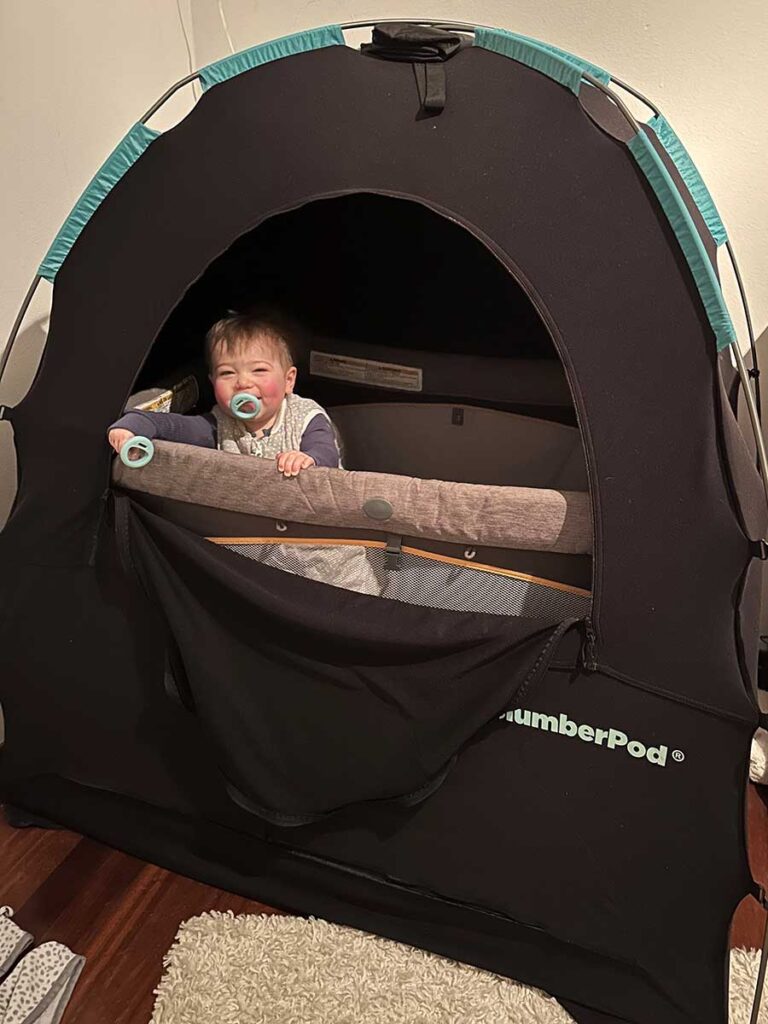 baby standing in travel crib in SlumberPod.