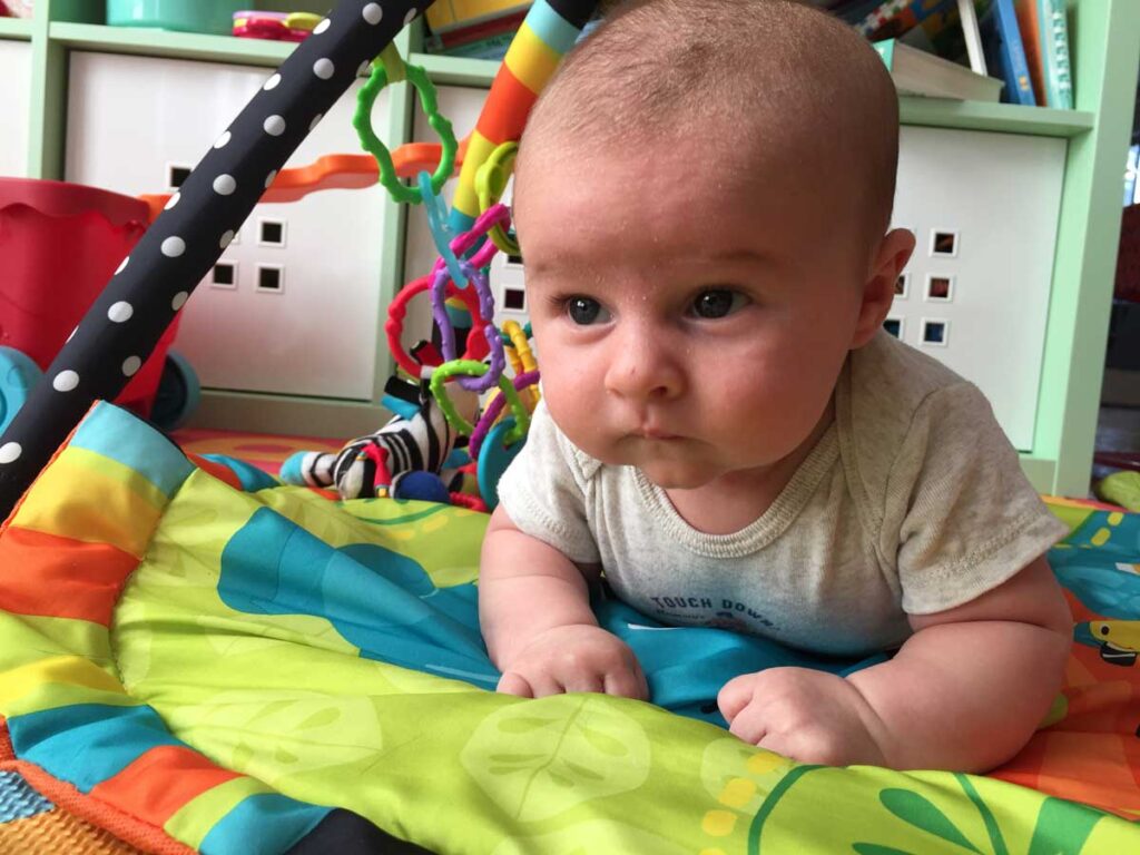 a baby from the BabyCanTravel.com family has tummy time on a portable play mat.