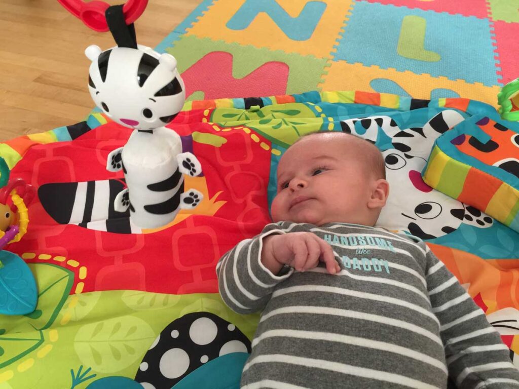 a baby from the BabyCanTravel..com family lies on his travel play mat.