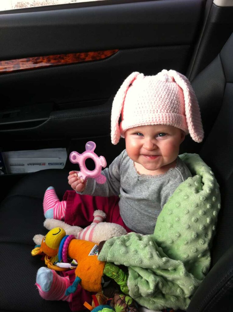 baby sitting in car playing with baby travel toys for car trips.