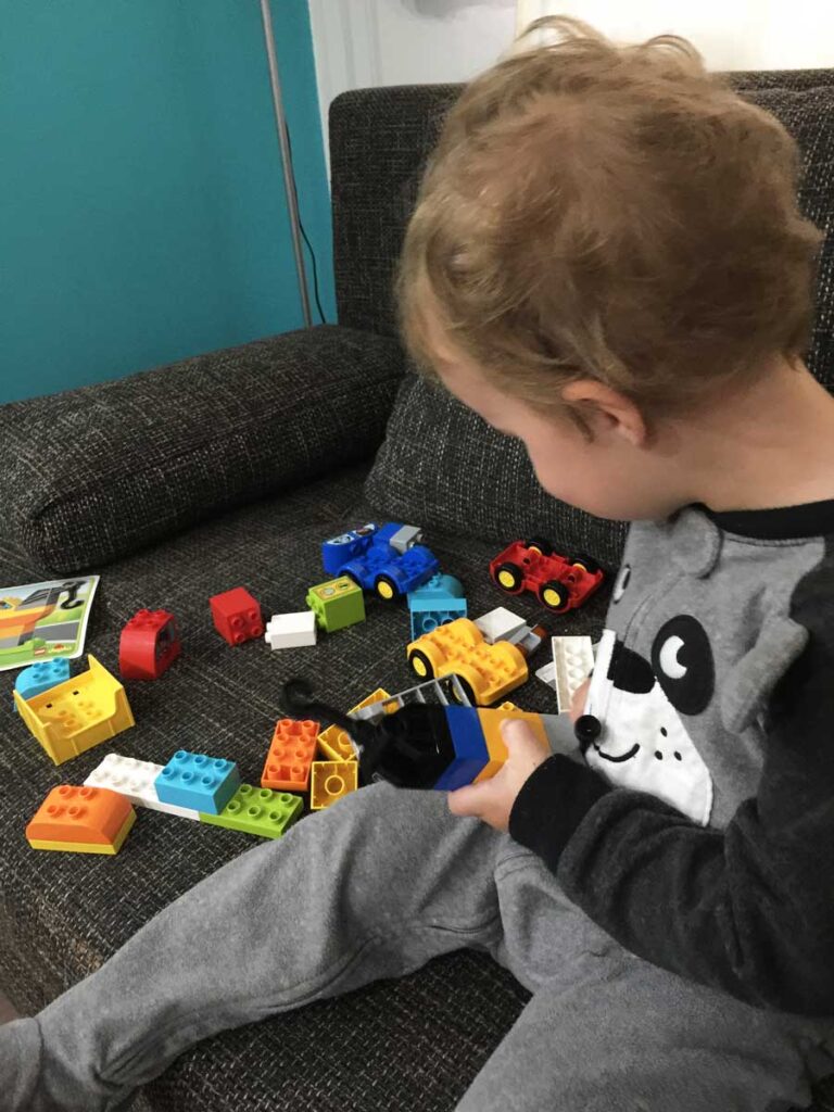 3 year old playing with Lego Duplo on a family vacation.