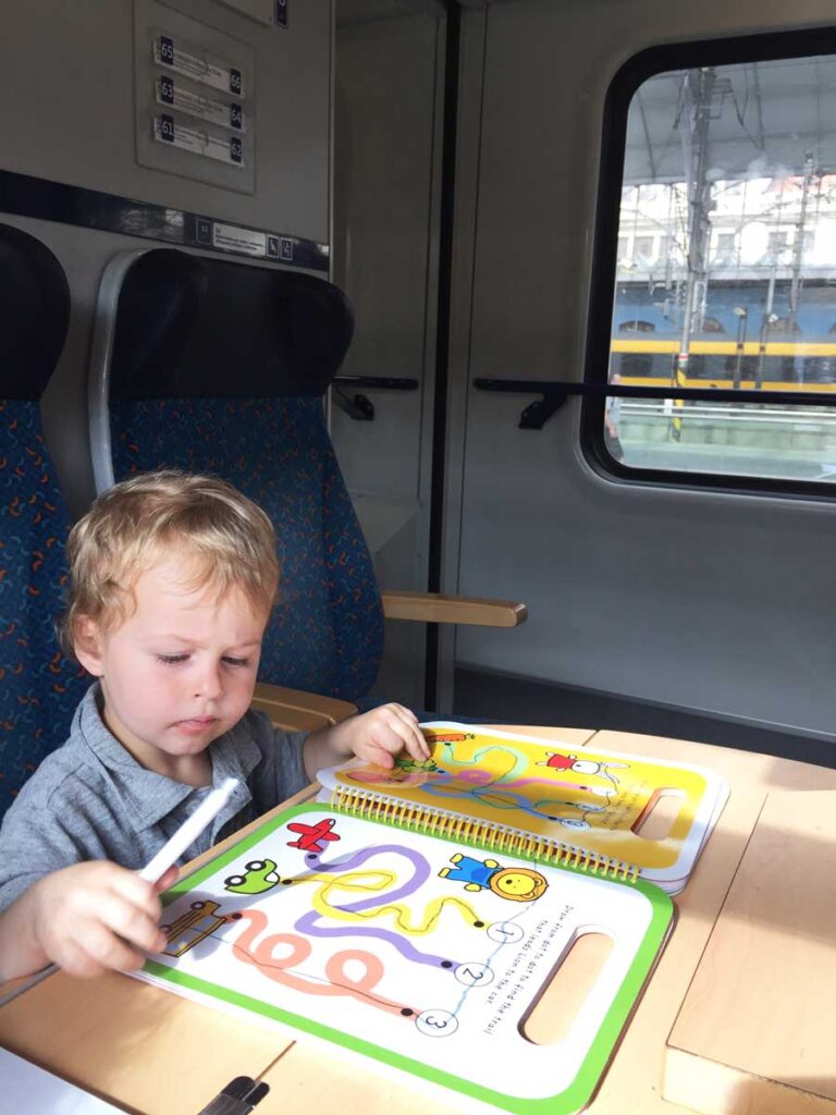 3 year old on train drawing in activity book