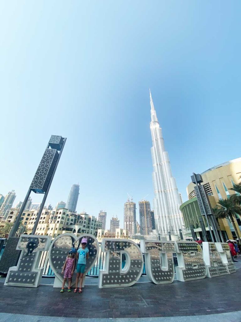 preschooler and toddler standing in front of Dubai sign