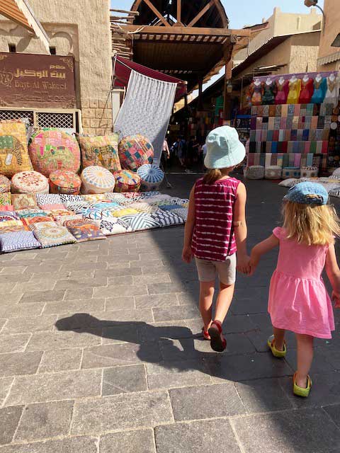 Toddler walking in Dubai holding hands with older sister