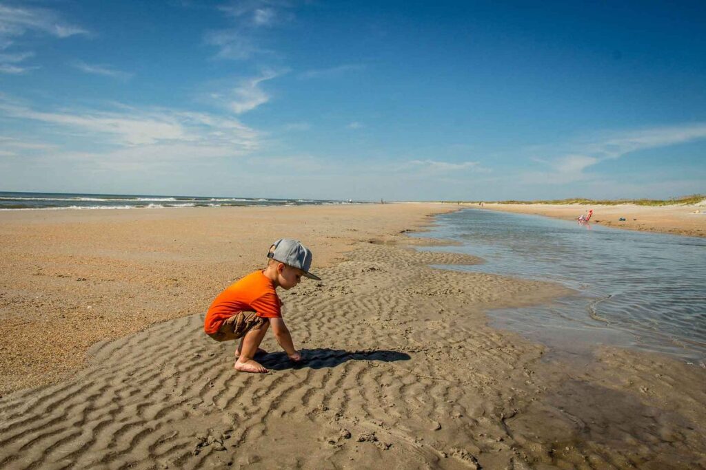 A toddler plays on the beach while on a family trip to Wilmington, North Carolina