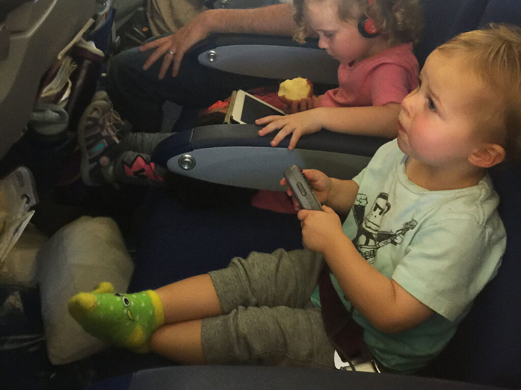 Toddler playing with remote on airplane.