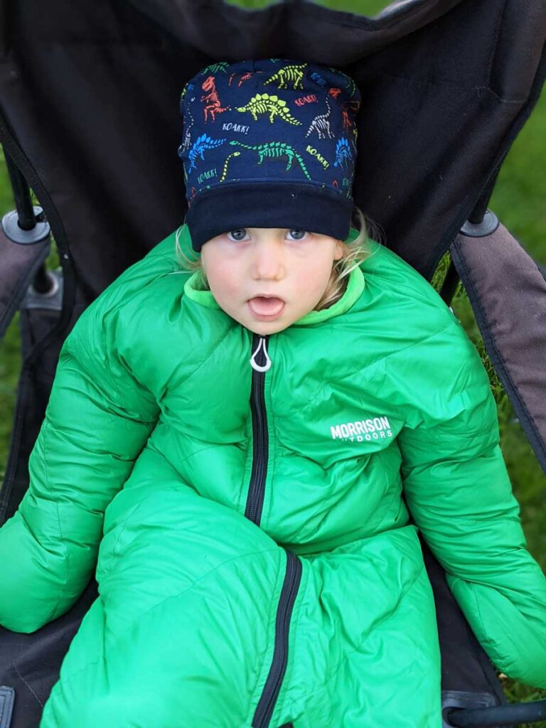 a toddler in a Morrison Outdoors Big Mo 20 Sleeping Bag for Toddlers on a family camping trip.