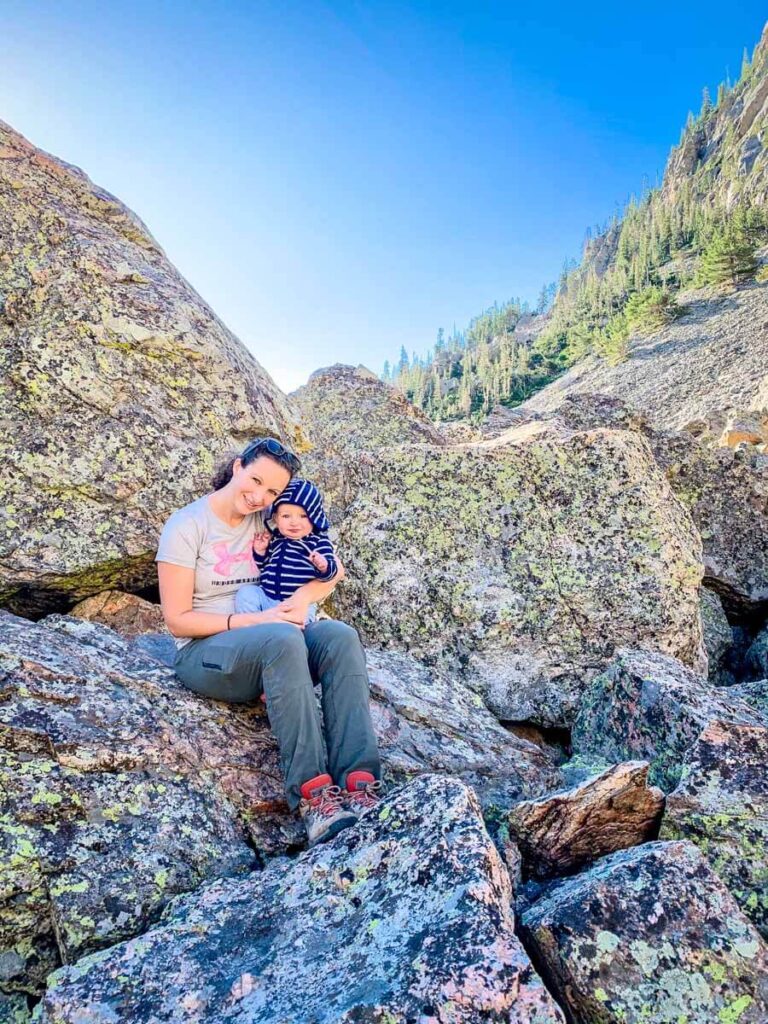 mother holding baby sitting on rocks - while Hiking in Rocky Mountain National Park with a baby - Bear Lake Hike