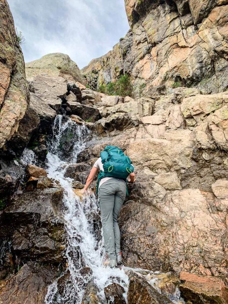 woman walking up side of waterfall on Sky Pond Hike in Rocky Mountain NP